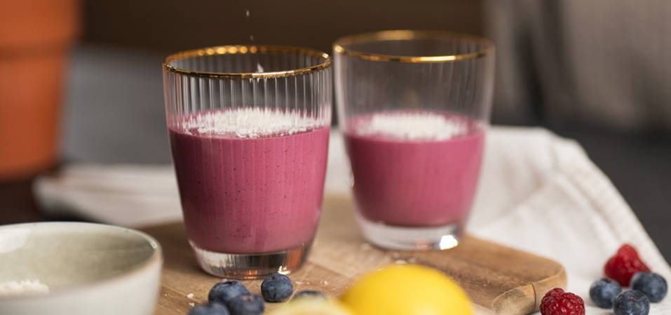 Zwei Gläser Beerensmoothie, Kokosraspeln.