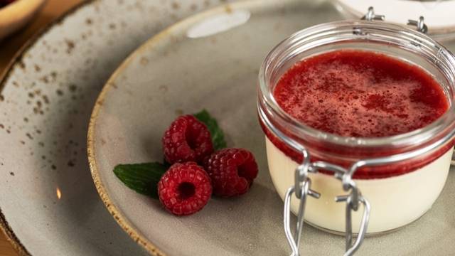 Panakotta mit Himbeersauce und frischen Himbeeren.
