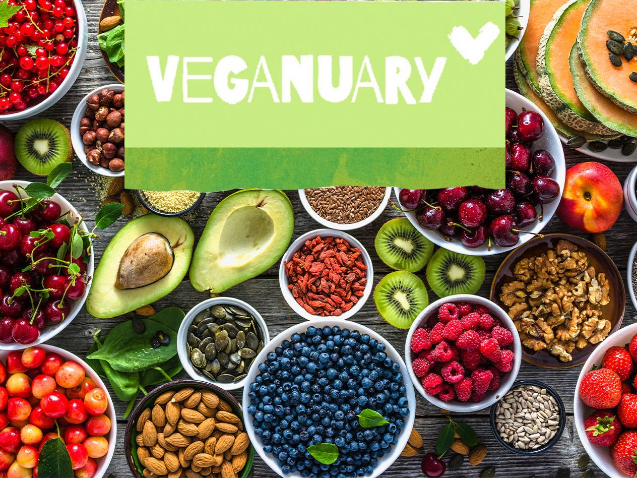 Eine Auswahl an frischem Obst, Nüssen und Samen mit dem Schriftzug 'VEGANUARY'.