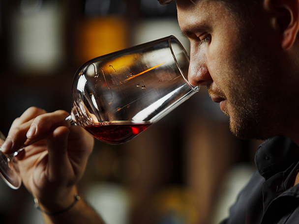 Mann riecht an einem Glas Rotwein