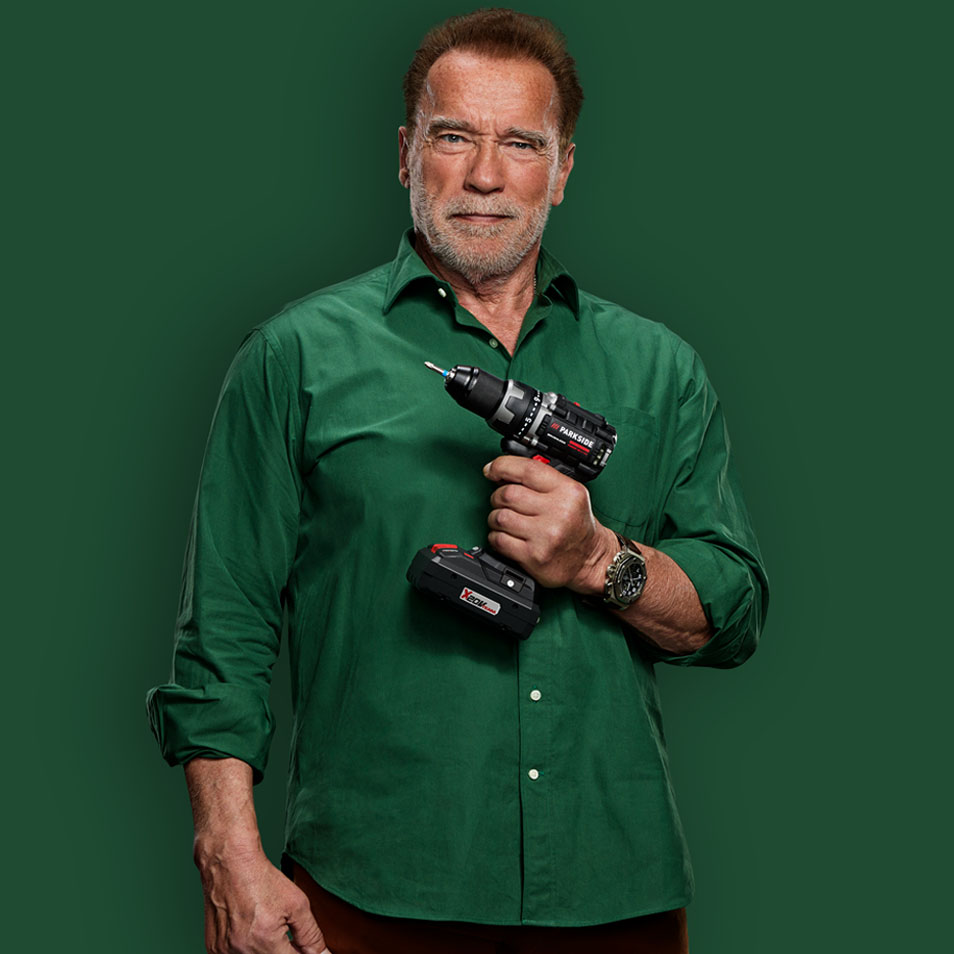 Arnold Schwarzenegger hält einen Parkside Akkubohrer.