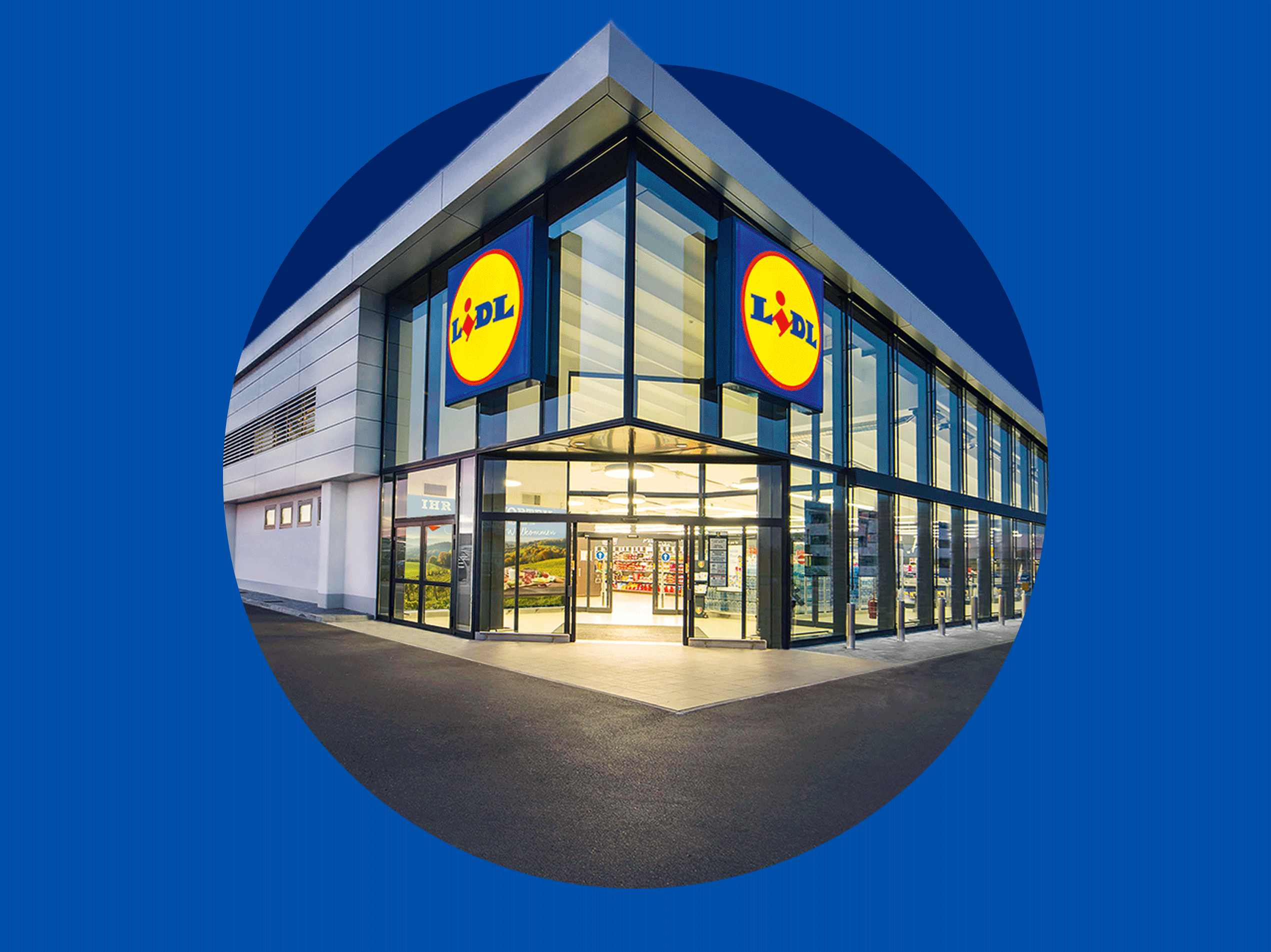 Modernes Supermarktgebäude mit großen Glasfenstern und beleuchtetem Eingang bei Nacht.